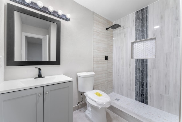 bathroom with tiled shower, toilet, and vanity