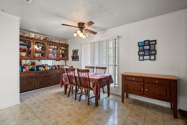 tiled dining room with a textured ceiling and ceiling fan