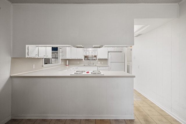 kitchen featuring white appliances, kitchen peninsula, sink, and white cabinets