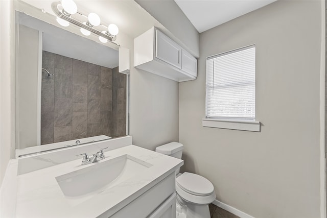 bathroom featuring tiled shower, vanity, and toilet