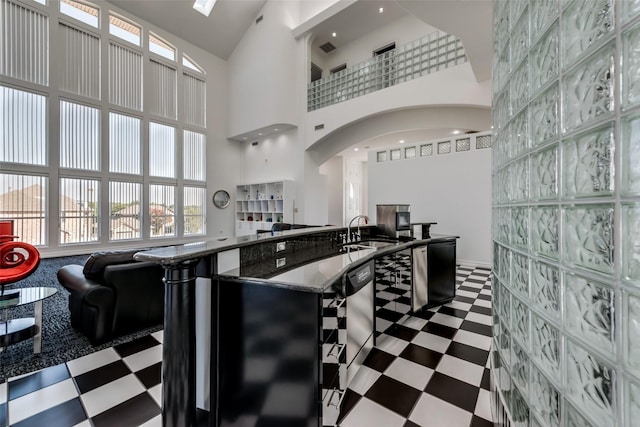 kitchen with tile patterned floors, open floor plan, arched walkways, a high ceiling, and a sink