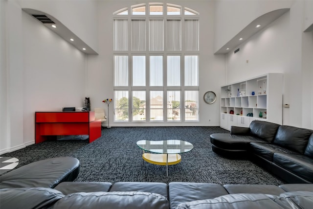 living area with a towering ceiling, carpet floors, recessed lighting, and baseboards