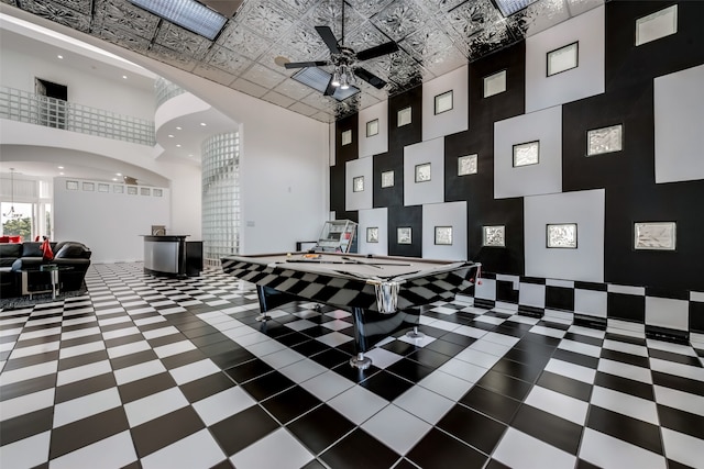 recreation room with a towering ceiling and ceiling fan