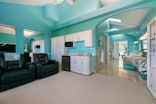 kitchen with a ceiling fan, black microwave, a sink, open floor plan, and white cabinets