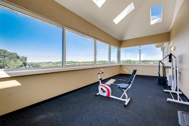 workout area featuring a skylight, lofted ceiling, and baseboards