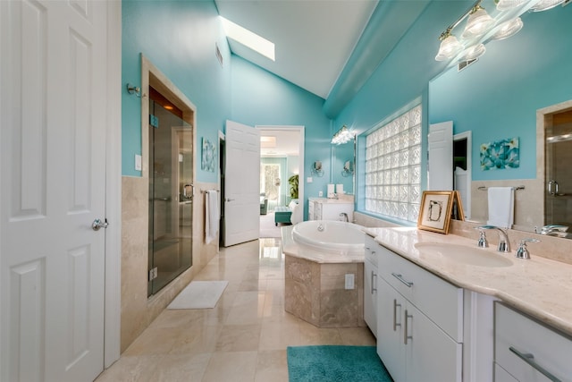 bathroom with lofted ceiling, a shower stall, a skylight, a bath, and two vanities