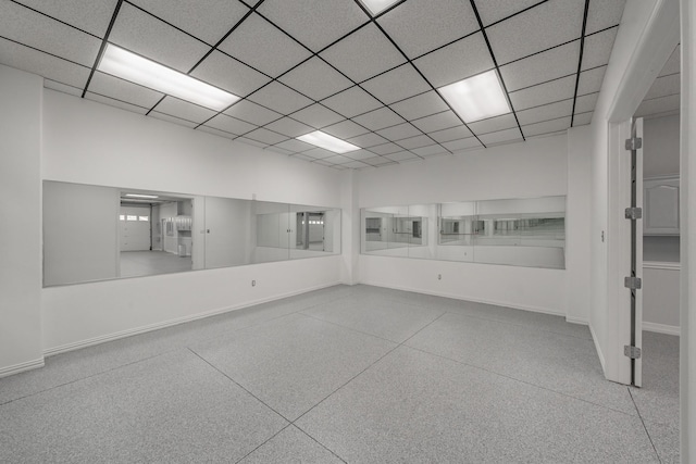 empty room with speckled floor, baseboards, and a drop ceiling