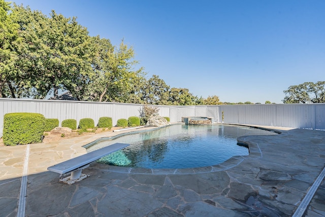 view of swimming pool featuring a fenced backyard, a pool with connected hot tub, a diving board, and a patio area