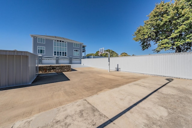 view of patio / terrace with basketball hoop and fence
