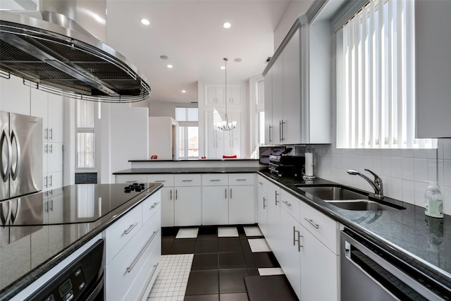 kitchen featuring appliances with stainless steel finishes, extractor fan, a sink, tasteful backsplash, and a chandelier