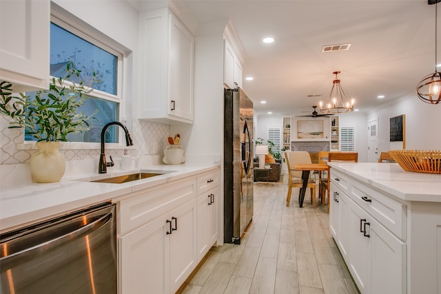 kitchen with sink, white cabinetry, hanging light fixtures, and appliances with stainless steel finishes