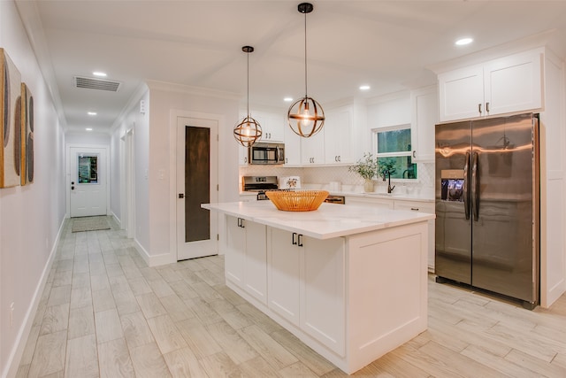 kitchen featuring white cabinets, hanging light fixtures, tasteful backsplash, a kitchen island, and stainless steel appliances