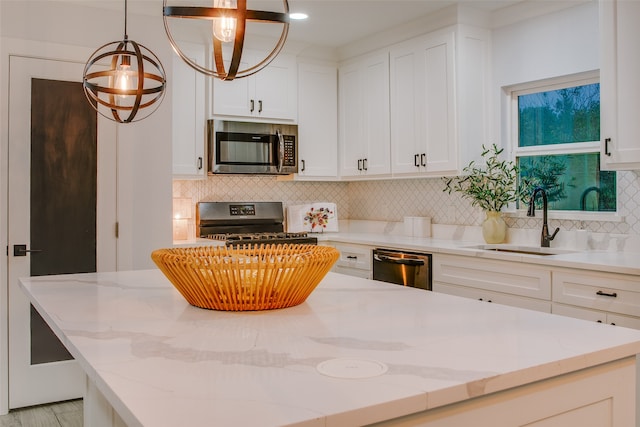 kitchen with decorative backsplash, pendant lighting, stainless steel appliances, and light stone countertops