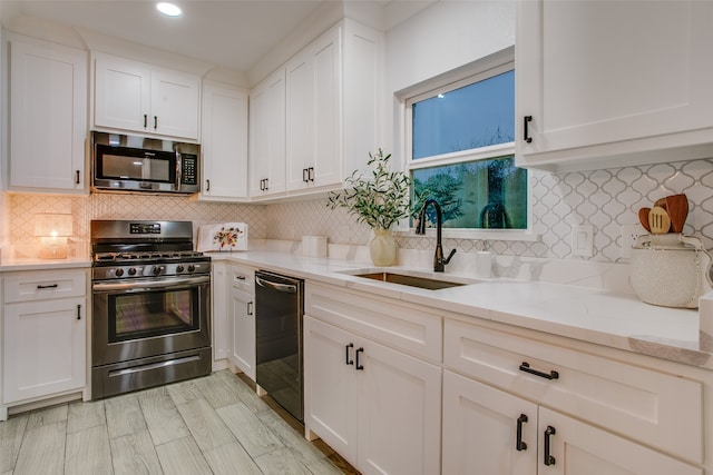 kitchen featuring sink, light stone countertops, tasteful backsplash, white cabinetry, and stainless steel appliances