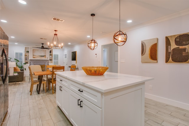 kitchen with white cabinetry, light stone counters, pendant lighting, light hardwood / wood-style floors, and a kitchen island