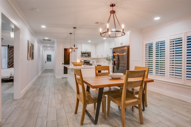 dining area with a notable chandelier, a barn door, light hardwood / wood-style floors, and ornamental molding