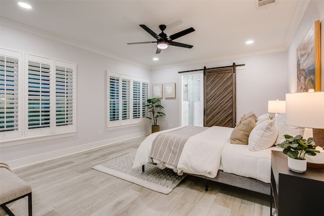 bedroom with a barn door, ceiling fan, crown molding, and light wood-type flooring