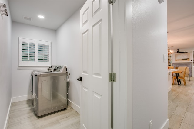 clothes washing area with independent washer and dryer, light wood-type flooring, and a notable chandelier