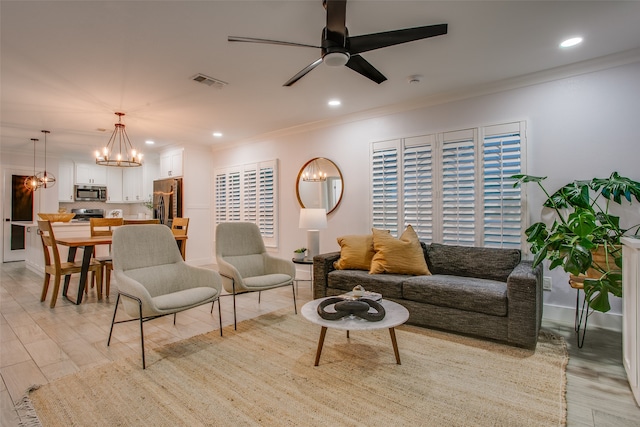 living room with ceiling fan with notable chandelier, light hardwood / wood-style floors, and crown molding