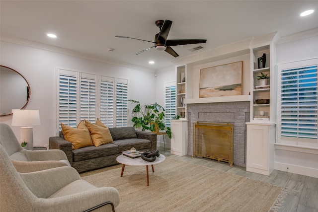 living room with a fireplace, ceiling fan, light hardwood / wood-style flooring, and ornamental molding