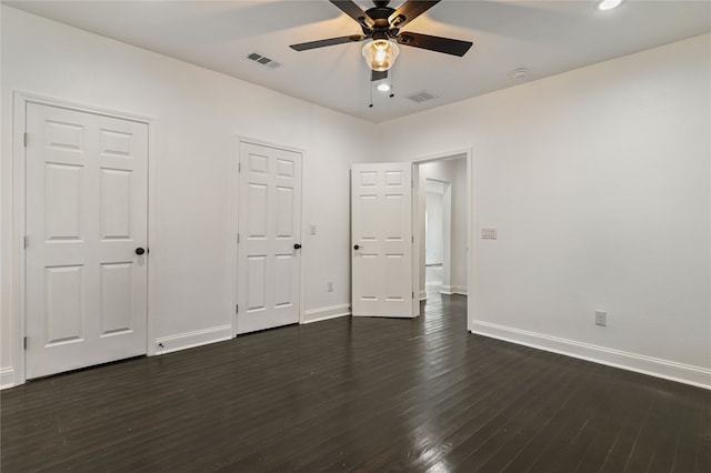 unfurnished bedroom featuring two closets, ceiling fan, and dark hardwood / wood-style flooring