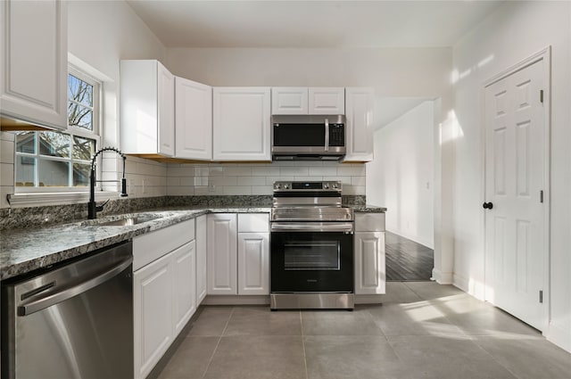 kitchen with white cabinetry, stainless steel appliances, sink, and backsplash