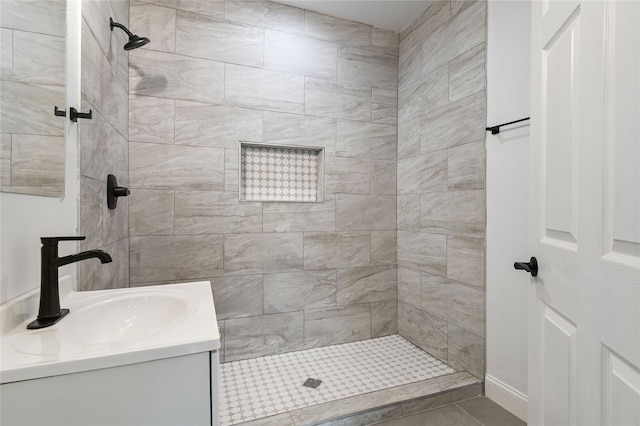 bathroom featuring tile patterned flooring, vanity, and a tile shower