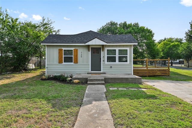 bungalow with a front yard and a wooden deck