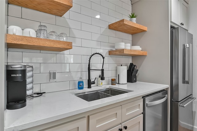 kitchen with backsplash, sink, light stone counters, and stainless steel appliances