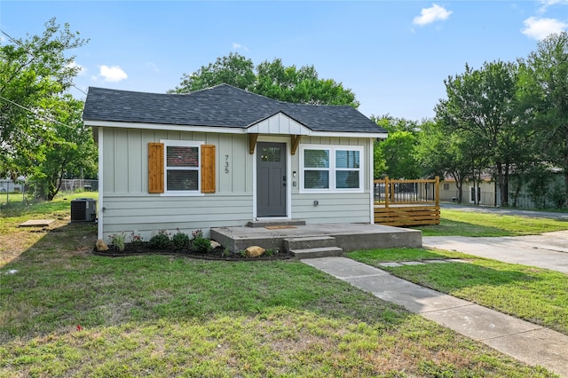 bungalow-style home featuring central AC unit, a front lawn, and a deck