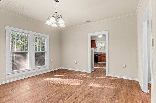 spare room with a wealth of natural light, hardwood / wood-style floors, a notable chandelier, and ornamental molding