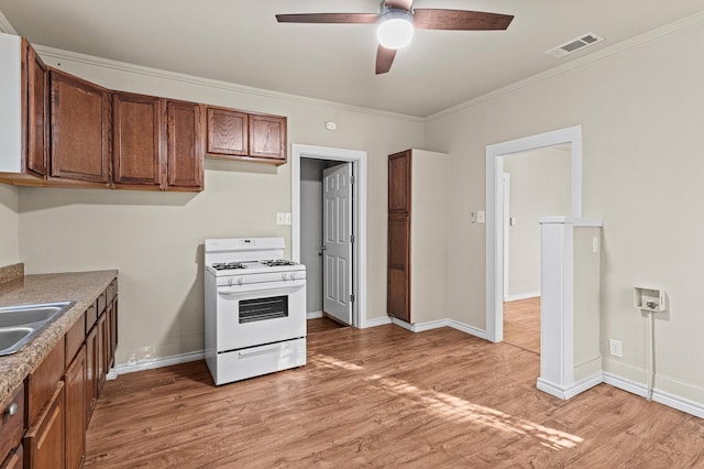 kitchen featuring light hardwood / wood-style floors, ceiling fan, white gas range oven, and ornamental molding