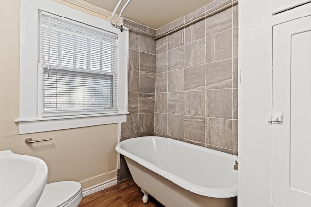 bathroom featuring toilet, a washtub, wood-type flooring, and a textured ceiling