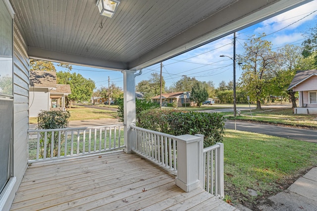 wooden terrace with a lawn and covered porch