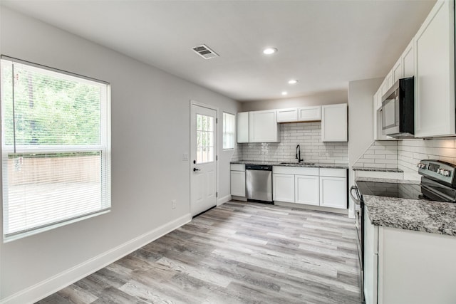 kitchen featuring sink, appliances with stainless steel finishes, light stone counters, white cabinets, and decorative backsplash