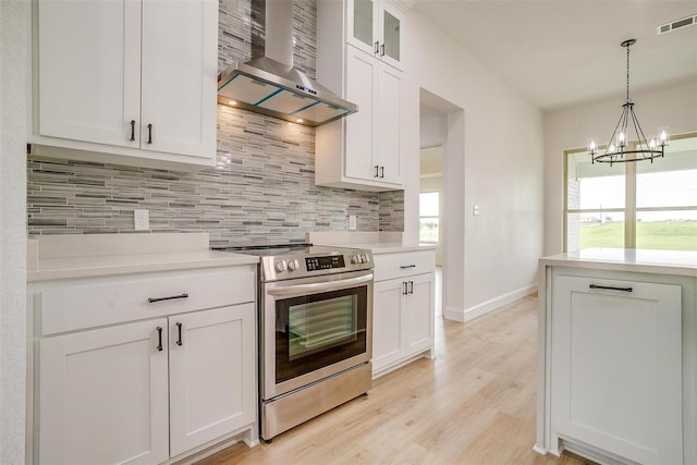 kitchen featuring light hardwood / wood-style floors, wall chimney range hood, a wealth of natural light, and electric stove