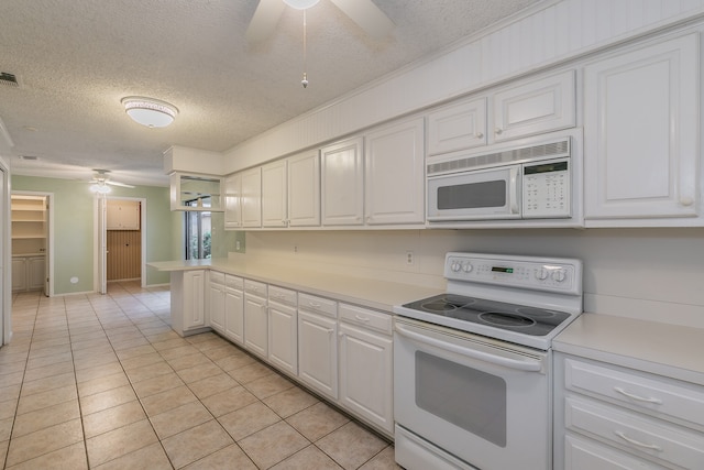 kitchen featuring white appliances, a textured ceiling, light tile patterned flooring, and white cabinets