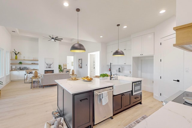 kitchen with white cabinetry, appliances with stainless steel finishes, light stone countertops, hanging light fixtures, and light hardwood / wood-style flooring