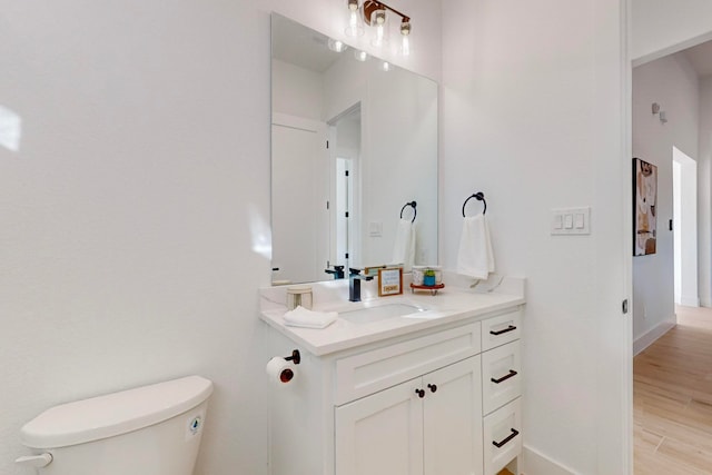 bathroom with toilet, vanity, and wood-type flooring