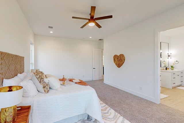 bedroom with connected bathroom, light colored carpet, and ceiling fan