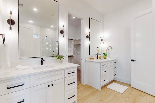 bathroom with hardwood / wood-style flooring, a shower with shower door, and vanity