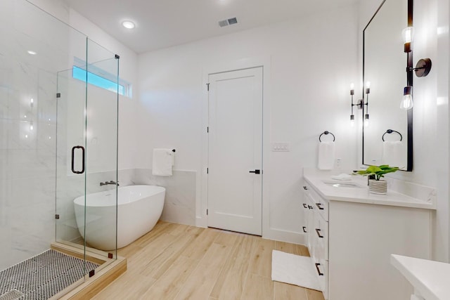 bathroom with hardwood / wood-style flooring, vanity, and separate shower and tub