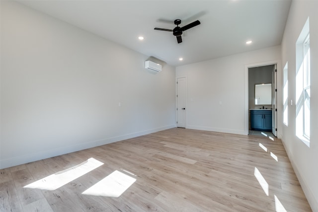 empty room featuring a wall unit AC, light hardwood / wood-style floors, and ceiling fan