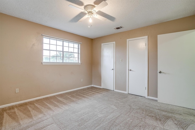 unfurnished bedroom with a textured ceiling, light carpet, and ceiling fan