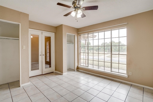 unfurnished bedroom with light tile patterned flooring, ceiling fan, a textured ceiling, and french doors