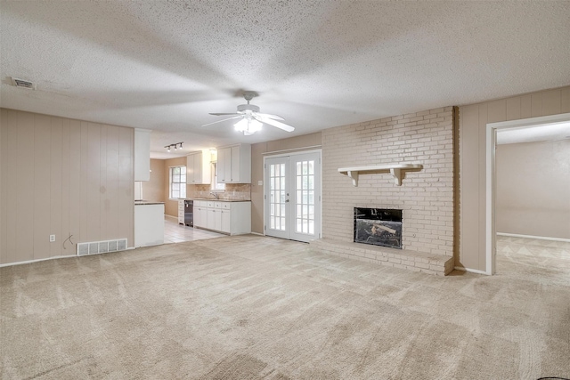 unfurnished living room featuring ceiling fan, light colored carpet, a textured ceiling, and french doors