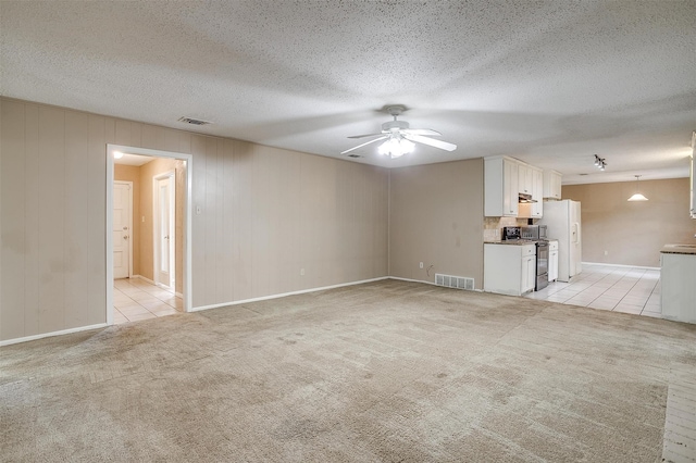 unfurnished living room with ceiling fan, light colored carpet, and a textured ceiling