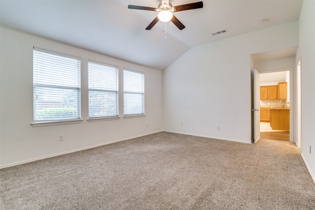 carpeted spare room featuring ceiling fan, sink, and lofted ceiling