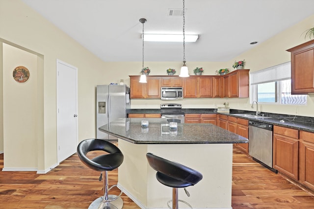 kitchen featuring stainless steel appliances, sink, a kitchen island, and hardwood / wood-style floors