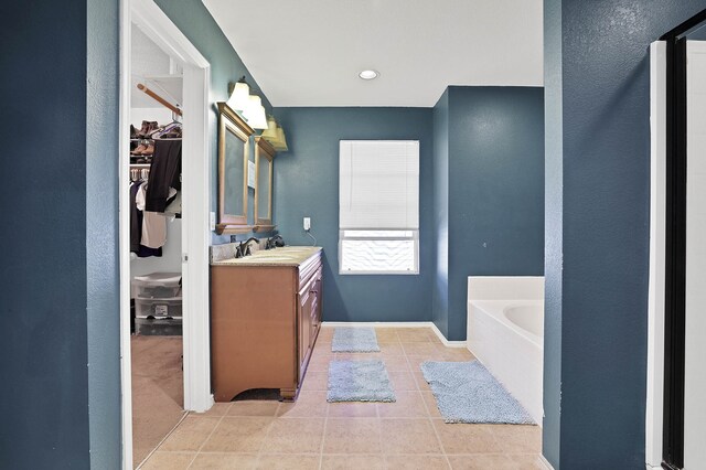 bathroom with a bathing tub, tile patterned flooring, and vanity